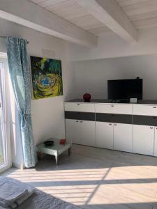 sala de estar con TV y armarios blancos en Un Capriccio - Ginepro, en Aieta