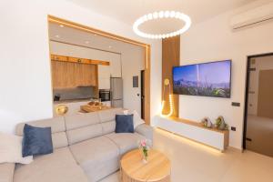 a living room with a white couch and a tv at City Compass Luxury Villa in Faliraki