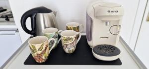 a coffee maker and four cups on a counter at A mi-chemin in Vannes