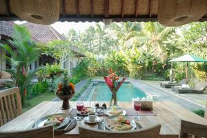 a table with food on it next to a swimming pool at Pondok Sebali Private Villa in Ubud