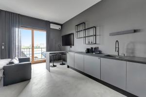 a kitchen with white cabinets and a living room at Apartament Gdańsk Premium Lux Nadmotławie in Gdańsk