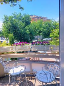 - deux chaises assises sur un balcon fleuri dans l'établissement B&B Romeo, à Santarcangelo di Romagna