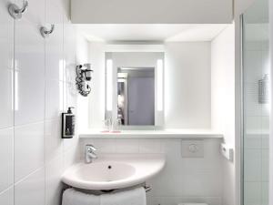 ein weißes Badezimmer mit einem Waschbecken und einem Spiegel in der Unterkunft ibis Nürnberg City am Plärrer in Nürnberg