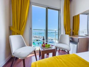 a bedroom with two white chairs and a table with a bowl of fruit at Dedeoğlu Port Hotel in Fethiye