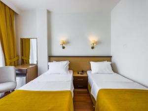 2 Betten in einem Hotelzimmer mit gelber Bettwäsche in der Unterkunft Dedeoğlu Port Hotel in Fethiye