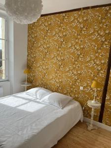 una camera con un letto bianco e una parete gialla di la maison Haute a Palluau-sur-Indre