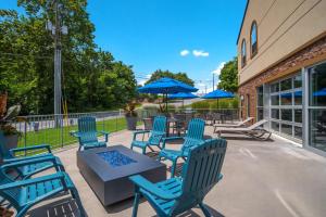 un patio con sillas y mesas azules y sombrillas azules en SureStay Plus Hotel by Best Western Elizabethtown Hershey, en Elizabethtown
