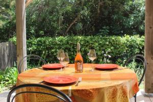 a table with red plates and a bottle of wine at MINI VILLA PALOMBAGGIA - Piscine chauffée in Porto-Vecchio