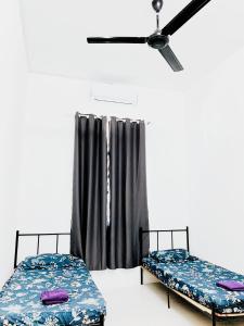 two beds in a room with a ceiling fan at D' Splash Garden Homestay in Baling