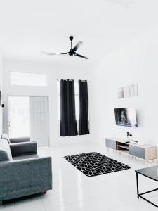 een witte woonkamer met een bank en een tv bij D' Splash Garden Homestay in Baling
