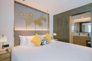 a bedroom with a large white bed with yellow pillows at Wyndham La Vita Rawai Phuket in Rawai Beach