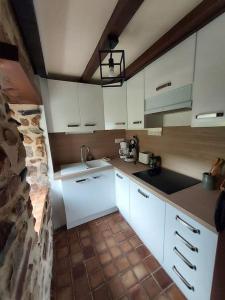 eine Küche mit weißen Schränken und einem Waschbecken in der Unterkunft SCIOTOT-BORD DE MER - LA GRANGE in Les Pieux