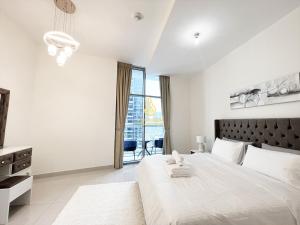 a white bedroom with a large bed and a large window at Marina Wharf II Dubai Marina - AL Maraseem in Dubai