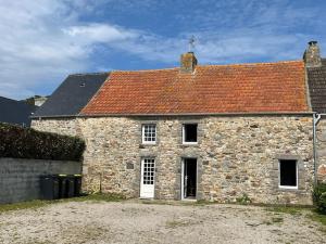 ein altes Steinhaus mit rotem Dach in der Unterkunft SCIOTOT-BORD DE MER - LA GRANGE in Les Pieux