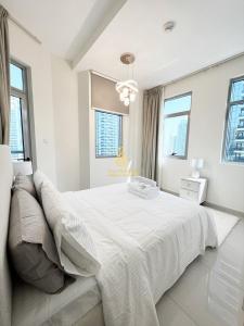 a white bedroom with a large white bed with windows at Marina Wharf II Dubai Marina - AL Maraseem in Dubai