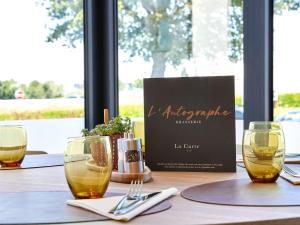 einen Tisch mit zwei Weingläsern und ein Menü darauf in der Unterkunft ibis Styles La Roche-sur-Yon in Mouilleron-le-Captif