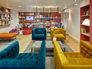 a library with yellow and blue couches and a table at ibis Styles La Roche-sur-Yon in Mouilleron-le-Captif