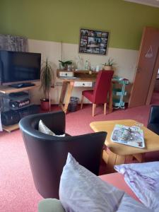 ein Wohnzimmer mit einem TV, einem Tisch und Stühlen in der Unterkunft Hübsches Zimmer nahe BER in Berlin