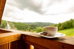 a cup of coffee sitting on a wooden rail next to a window at Chata Odskocznia in Wisła