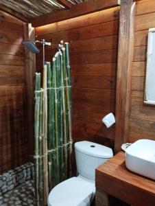 a bathroom with a toilet and a bamboo wall at ECOVILLA CORAL GARDEN in Baoruco