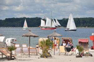 a group of people sitting on the beach with sailboats at Seaside in Laboe