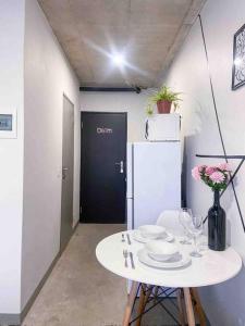 a white table with chairs and a white refrigerator at Cozy escape bachelor in Maboneng + uncapped WI-FI. in Johannesburg