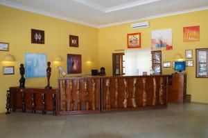 a lobby with yellow walls and a woman sitting at a desk at Lemon Creek Hotel Resort in Bijilo