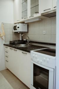 a white kitchen with a sink and a stove at Apartman Hana in Gornja Toplica