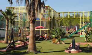 park z placem zabaw ze zjeżdżalnią i palmami w obiekcie 6/8 pax COTTAGE - Oasis Village w mieście Puget-sur Argens