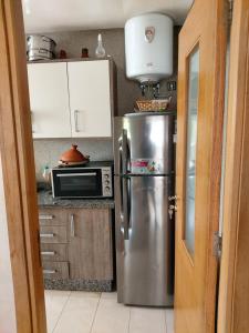 a kitchen with a stainless steel refrigerator and a microwave at Blanca Beach bel appartement avec wifi et Parking in Sidi Rahal