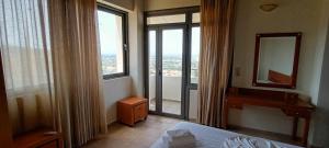 Schlafzimmer mit einem Bett, einem Spiegel und einem Fenster in der Unterkunft Hercules Hills Sea View Villas in Kos-Stadt
