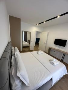 Cama blanca en habitación con espejo en Suite Hotel en Shëngjin