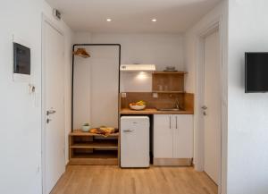 a small kitchen with white cabinets and a refrigerator at Aiora Suites in Psakoudia