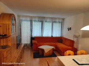 uma sala de estar com um sofá vermelho e uma mesa em Haus Azurit Wohnung Nr.25 em Grächen