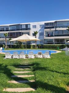 una piscina con sillas y una sombrilla y un edificio en Blanca Beach bel appartement avec wifi et Parking, en Sidi Rahal