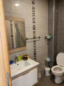 a bathroom with a sink and a toilet and a mirror at Blanca Beach bel appartement avec wifi et Parking in Sidi Rahal