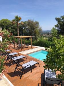 een houten terras met stoelen en een zwembad bij Pool Oasis with Mountain Views in Maçanet de la Selva