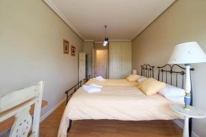 um quarto com uma cama grande e um candeeiro. em Apartamento frente al Sardinero em Santander