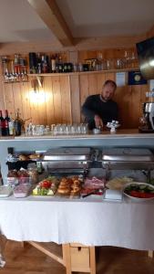 Un uomo in piedi dietro un bancone in una cucina con cibo di Stile Oase Apartment 1 a Bruck an der Grossglocknerstrasse