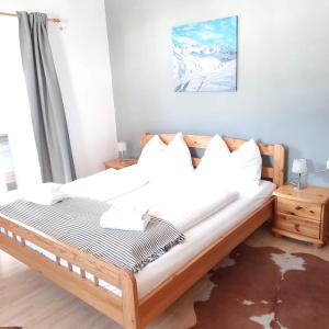 a bedroom with a bed with white sheets and pillows at Stile Oase Apartment 1 in Bruck an der Großglocknerstraße +11 photos