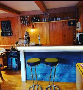 a bar with two stools in front of a counter at Stile Oase Apartment 1 in Bruck an der Großglocknerstraße