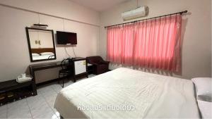 Habitación de hotel con cama y espejo en Thaen Thong Hotel en Lamphun