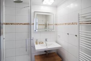a white bathroom with a sink and a mirror at Panorama Schönberger-Strand Appartement 21 in Stakendorfer Strand +17 photos