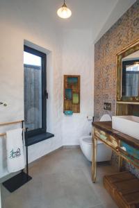 baño con lavabo y aseo y ventana en The Hut Retreat, en Fîntînele