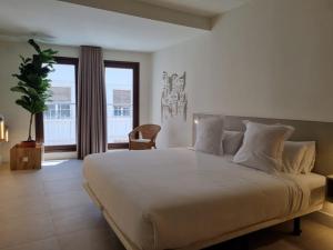 a bedroom with a large white bed and a window at Reina Victoria Velázquez in Alicante