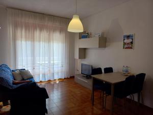 sala de estar con sofá, mesa y TV en Grazioso Bilocale Caletta Castiglioncello - Tuscany en Castiglioncello