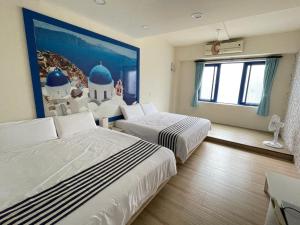 een hotelkamer met 2 bedden en een schilderij aan de muur bij Meet ‧ Happiness B&B in Donggang