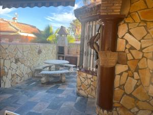 a patio with a picnic table and a stone wall at Chalet , a 6km de la playa in Chiclana de la Frontera