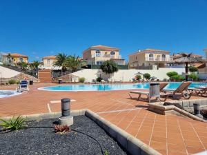 a swimming pool in a resort with chairs and umbrellas at Villa Maracay-Caleta de Fuste-fiber optic 600mb in Caleta De Fuste