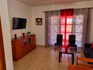 a living room with a couch and a tv at Villa Maracay-Caleta de Fuste-fiber optic 600mb in Caleta De Fuste